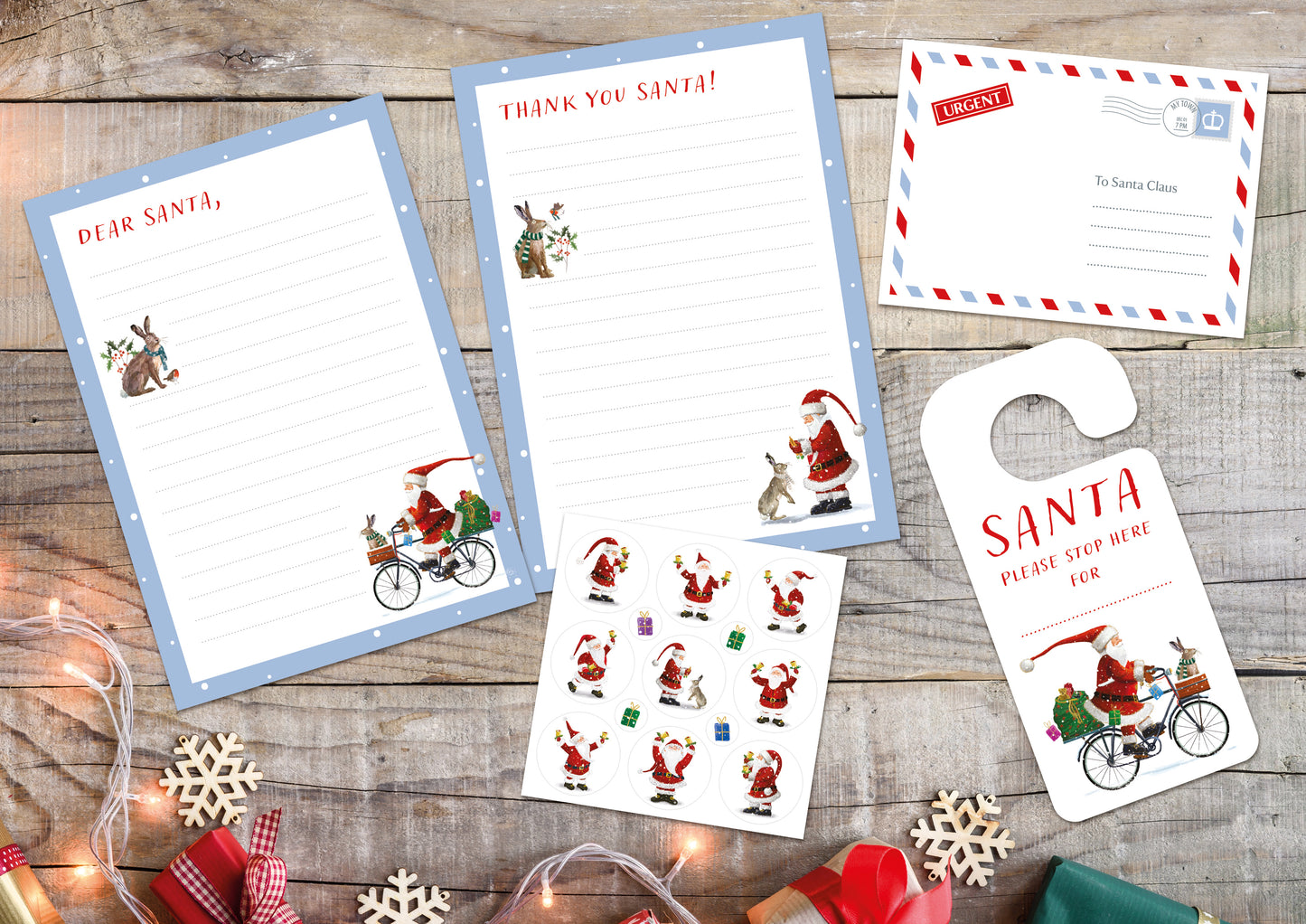 Two sheets of letter paper with a light blue boarder. The letter paper with red text at the top that reads "Dear Santa," features illustrations of a hare wearing a knitted scarf with a sprig of holly and a robin, and Santa riding a bicycle laden with presents and a hare in a knitted scarf sitting in the basket. The letter paper with red text at the top reads "thank you Santa!" features illustrations of a hare wearing a knitted scarf with a sprig of holly and a robin